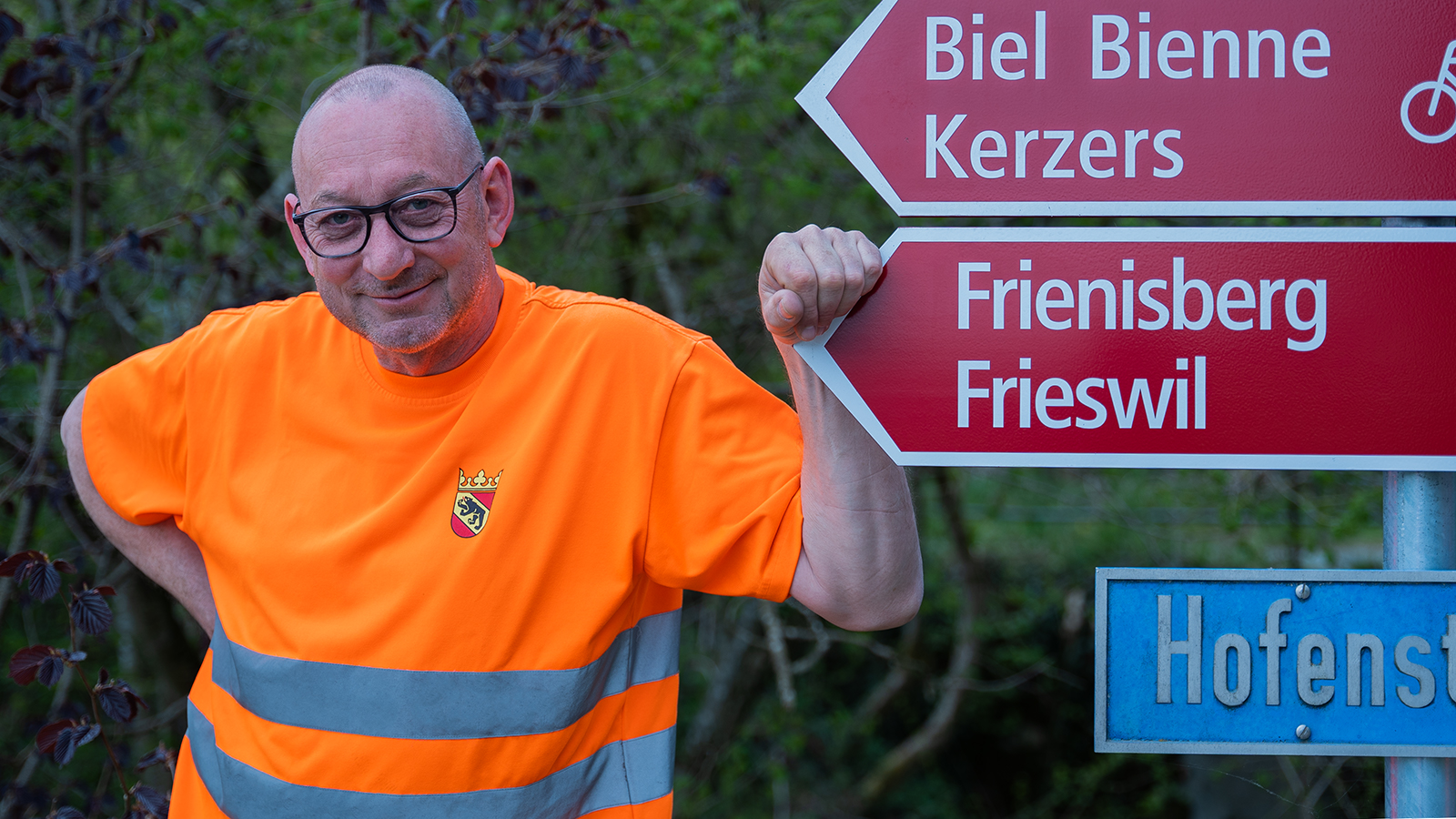 Alfred Stettler debout à côté de panneaux indicateurs de pistes cyclables.